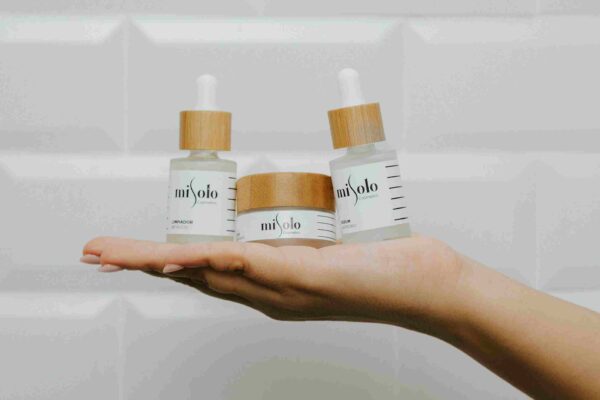 A minimalist display of skincare products from MiSolo Cosmetics, featuring a serum, a moisturizer, and a facial cleanser in glass containers with bamboo lids. Best Facial Serums For Dry Skin - Hydrating and nourishing formulas for a glowing complexion