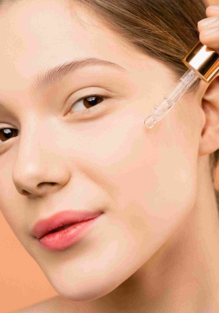 A close-up of a woman with smooth, radiant skin applying a hydrating facial serum using a dropper. Best Facial Serums For Dry Skin - Lightweight and moisturizing skincare for a healthy glow.